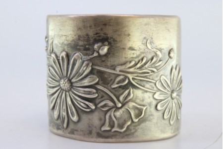 Argola de guardanapo em prata com motivos florais relevados.